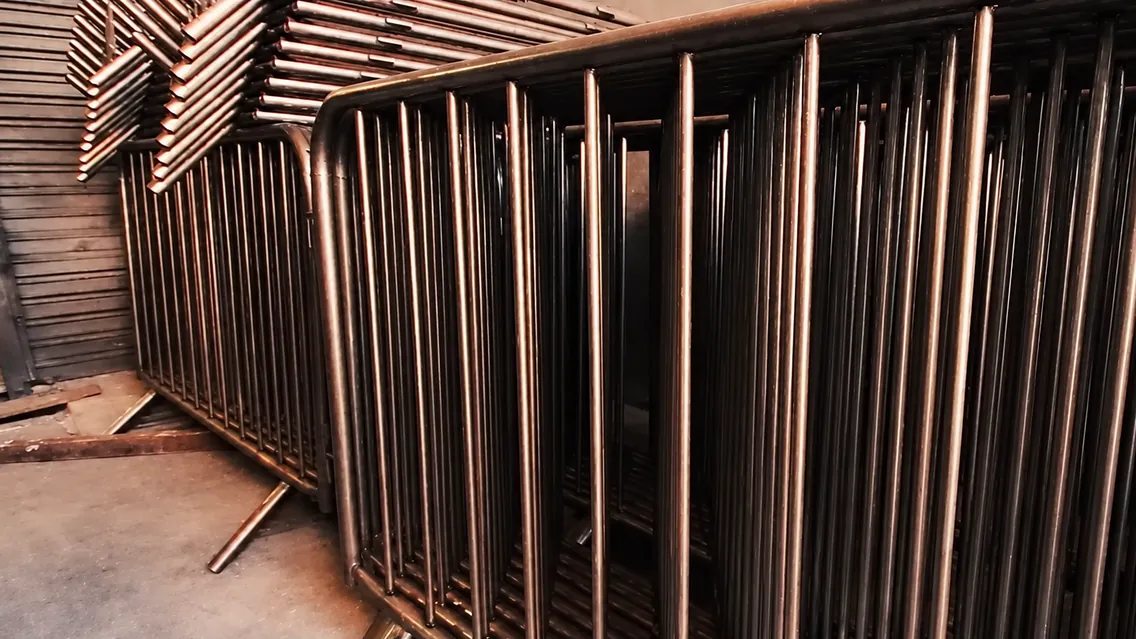 Grades de isolamento recém-soldadas, ainda sem galvanização, enfileiradas na fábrica, com quadros empilhados ao fundo